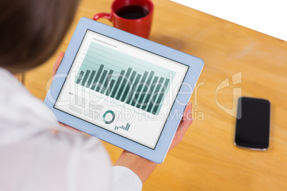 Composite image of businesswoman using tablet at desk