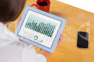 Composite image of businesswoman using tablet at desk