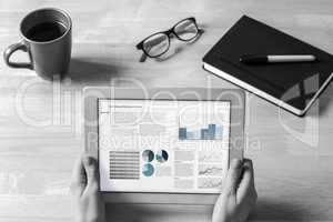 Composite image of businesswoman holding tablet at desk