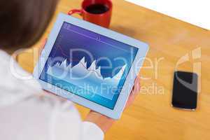 Composite image of businesswoman using tablet at desk