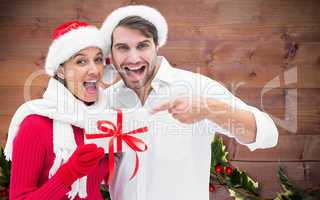 Composite image of festive young couple holding gift