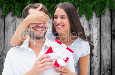 Composite image of woman surprising boyfriend with gift