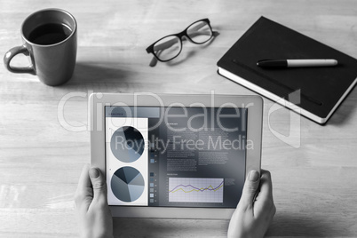 Composite image of businesswoman holding tablet at desk