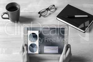 Composite image of businesswoman holding tablet at desk