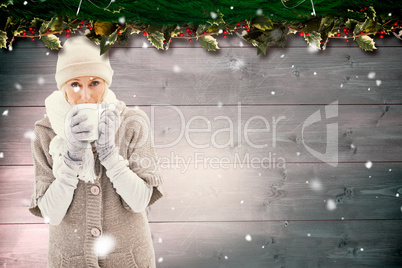 Composite image of woman in warm clothing holding mugs