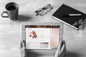 Composite image of businesswoman holding tablet at desk