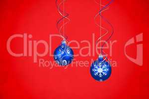 Composite image of two hanging blue bauble decorations