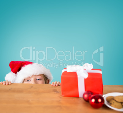 Composite image of festive boy peeking over table