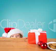 Composite image of festive boy peeking over table