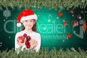 Composite image of festive little girl smiling at camera holding