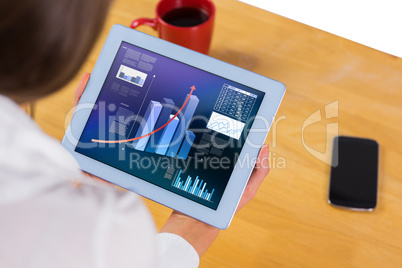 Composite image of businesswoman using tablet at desk