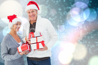 Composite image of festive mature couple holding christmas gifts