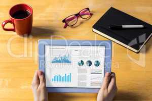 Composite image of businesswoman using tablet at desk