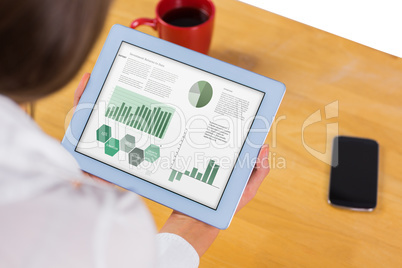 Composite image of businesswoman using tablet at desk