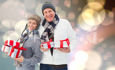 Composite image of festive mature couple holding christmas gifts