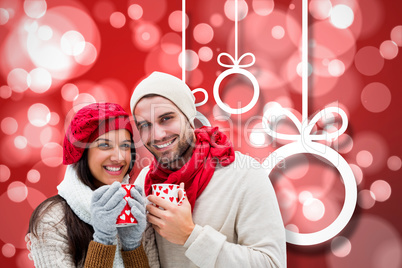 Composite image of winter couple holding mugs