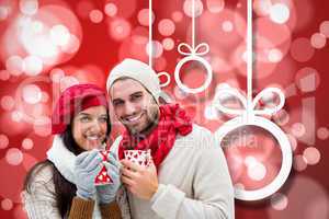 Composite image of winter couple holding mugs