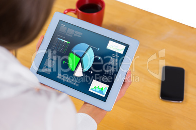 Composite image of businesswoman using tablet at desk