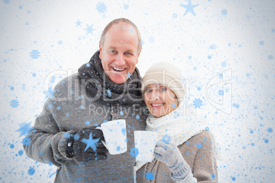 Happy mature couple in winter clothes holding mugs