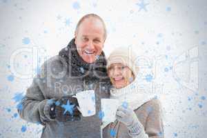 Happy mature couple in winter clothes holding mugs