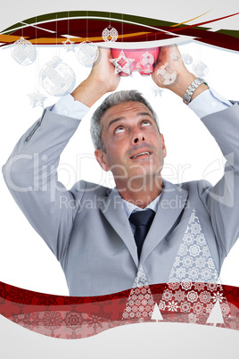 Composite image of curious businessman holding piggy bank above