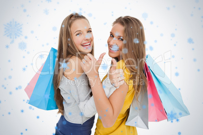 Rear view of two young women the thumbup with shopping bags