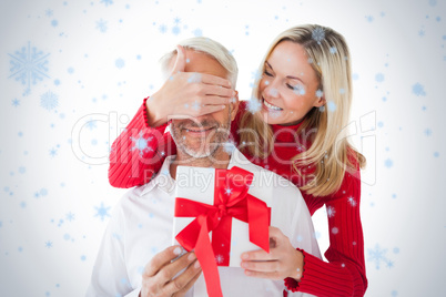 Smiling woman covering partners eyes and holding gift