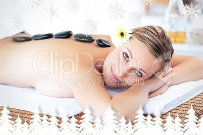 Glowing young woman with hot stone on her back smiling at the ca
