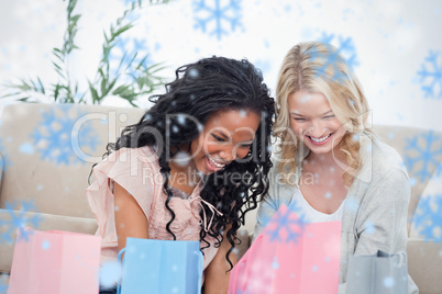 Two smiling women sitting on the floor with shopping bags