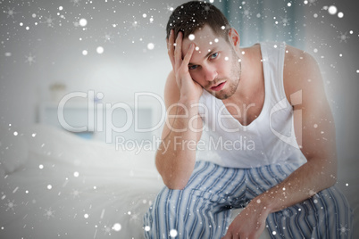 Composite image of depressed man sitting on his bed