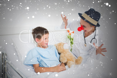 Doctor in clown costume entertaining ill boy in hospital