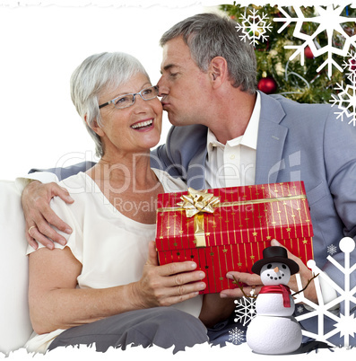 Senior man giving a kiss and a christmas present to his wife