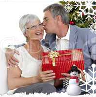 Senior man giving a kiss and a christmas present to his wife