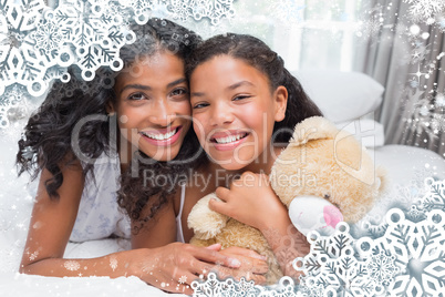 Pretty woman lying on bed with her daughter smiling at camera