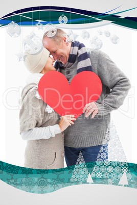 Happy mature couple in winter clothes holding red heart