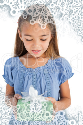 Composite image of cute little girl holding a wrapped gift