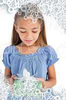 Composite image of cute little girl holding a wrapped gift