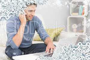 Smiling man using cellphone and laptop in living room