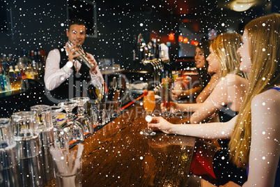 Handsome bartender making cocktails for attractive women