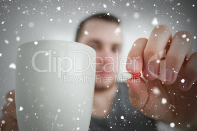 Composite image of man showing a pill and and a mug