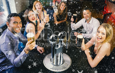 Composite image of laughing friends raising their glasses up