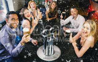 Composite image of laughing friends raising their glasses up