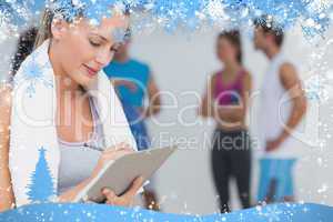 Trainer writing on clipboard with fitness class in background at