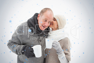 Happy mature couple in winter clothes holding mugs