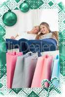 Composite image of smiling girls sitting on the couch with their bags of shopping