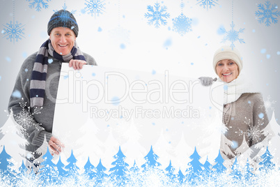 Mature couple in winter clothes holding card