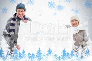 Mature couple in winter clothes holding card