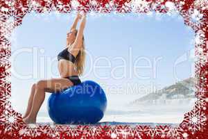 Fit blonde sitting on exercise ball at the beach