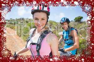 Fit couple cycling up mountain trail smiling at camera