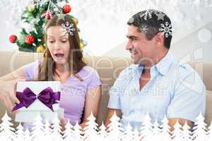 Composite image of surprised woman opening christmas present